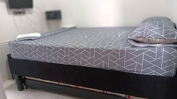 A bed with a geometric patterned bedspread, a pillow, and a TV mounted on the wall.