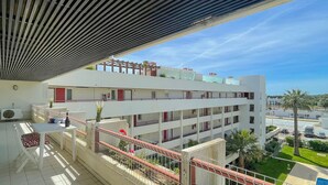 Un hôtel à plusieurs étages doté de balcons, d’un espace extérieur couvert aménagé en coin salon et offrant une vue sur les environs.