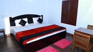 Een slaapkamer met een bed, een houten tafel en een stoel.