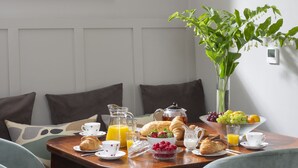 A breakfast table with croissants, fruit, and juice, set in a room with a window and a plant. - The Garden Rooms @ Drumagosker Rural Retreats (Limavady)