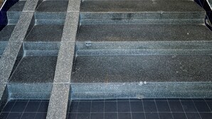 Un escalier dont les murs sont recouverts de carreaux bleus et qui se termine par une porte en bois.