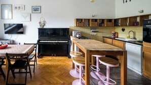 Une cuisine équipée d’un piano, de tabourets de bar en bois, d’une table à manger et d’un téléviseur.