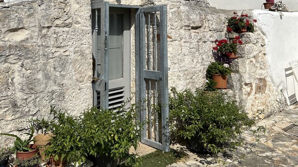 A stone building with a conical roof, a door, and potted plants. - Trullo holiday house Apulia with above ground pool (Ceglie Messapica)