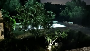 A nighttime view of a garden with a pool, stone pathway, and benches. - Trullo holiday house Apulia with above ground pool (Ceglie Messapica)