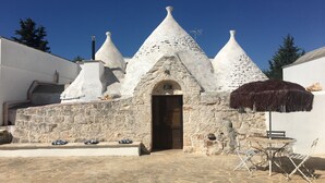 A traditional stone building with a central door and multiple conical roofs. - Trullo holiday house Apulia with above ground pool (Ceglie Messapica)