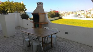 Um pátio externo com churrasqueira, mesa e cadeiras.