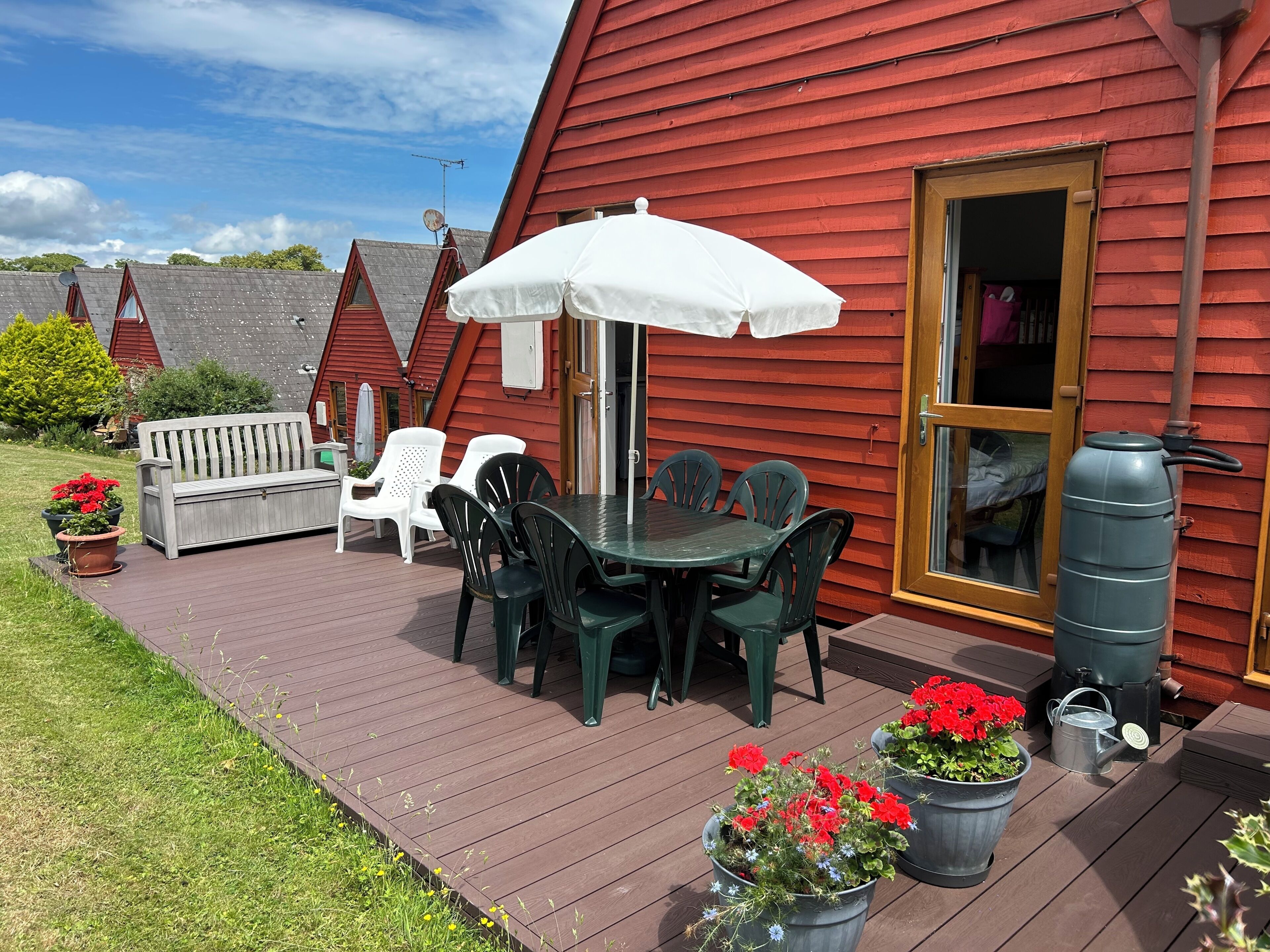 A deck with a table and chairs, a bench, and potted plants.