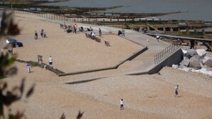 Une plage avec une promenade en bois, des bancs et une côte rocheuse.