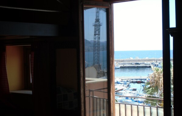 A balcony with a view of a marina, including boats and a distant tower. - Holidays in direct contact with the marine reserve, archaeological sites, cultural centers (Santa Flavia)