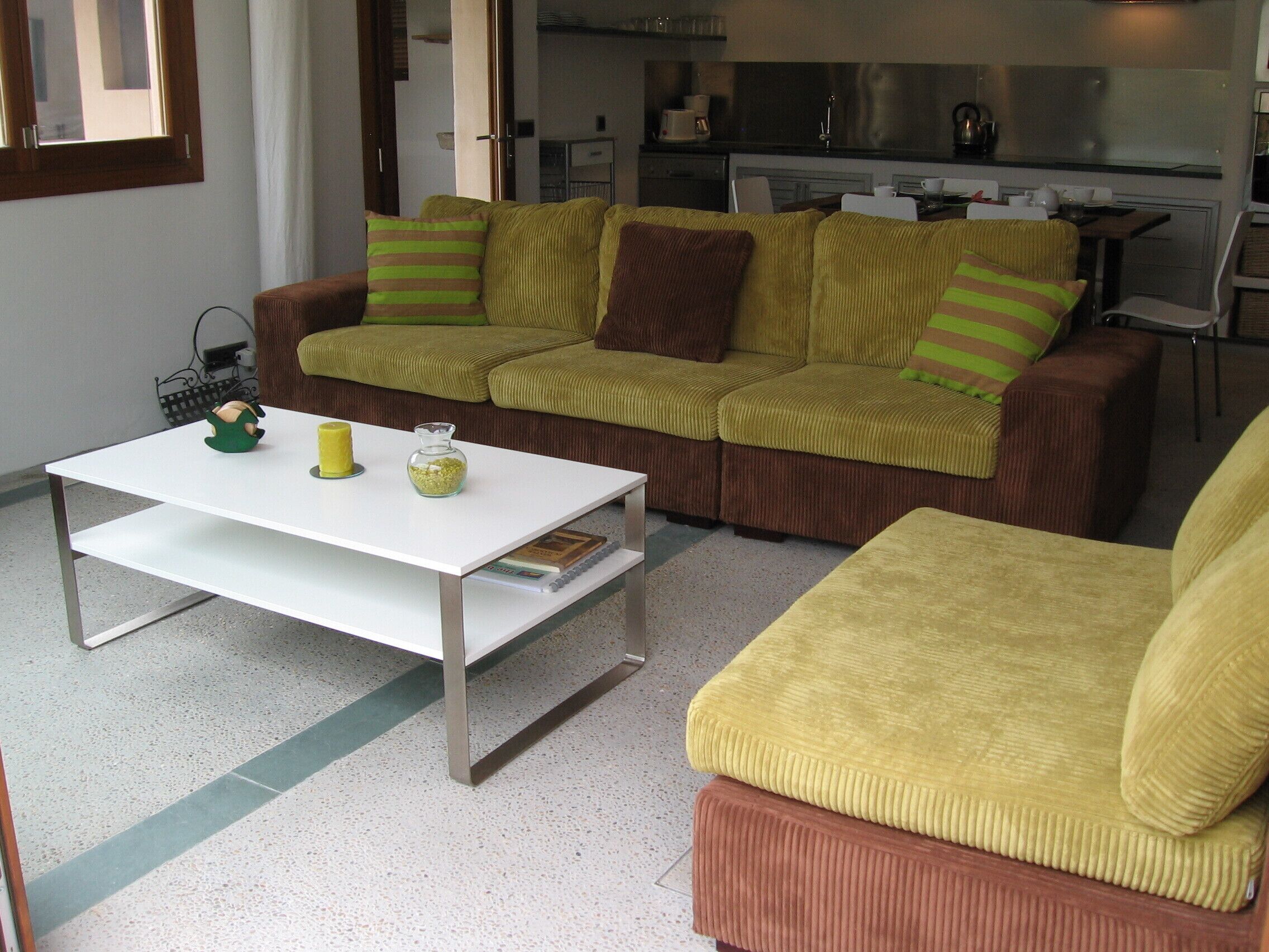 A living room with a sofa, a coffee table, and a kitchen in the background.