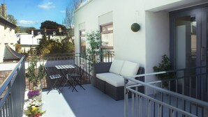 A balcony with a sofa, chairs, and potted plants. - Central Sidmouth studio apartment with Sea Peeps (Sidmouth)