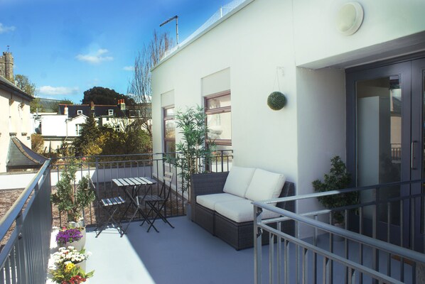 Un balcon avec un canapé, des chaises et des plantes en pot.
