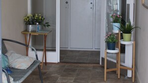 A small, enclosed room with a door, a chair, and potted plants. - Central Sidmouth studio apartment with Sea Peeps (Sidmouth)