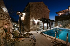 Un bâtiment en pierre doté d’une piscine, d’un espace extérieur aménagé et d’un escalier menant à un niveau supérieur.