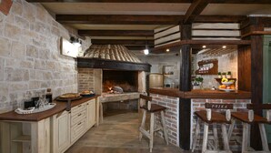 Une cuisine rustique avec un four en briques, des tabourets de bar en bois et un mur en pierre.