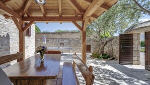 Un espace extérieur aménagé pour les repas, avec des murs en pierre et un bâtiment en pierre en arrière-plan.