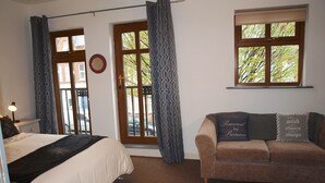 Un dormitorio con cama, sofá, ventana y puerta.
