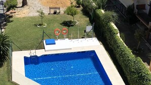 Une piscine rectangulaire à l’eau d’un bleu limpide, entourée d’une terrasse carrelée de couleur blanche.