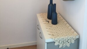 Un baño con un mueble blanco, un espejo grande y tres ganchos negros para toallas.