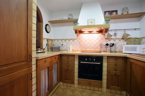 Une cuisine avec des meubles en bois, un four à micro-ondes, un grille-pain et une horloge au mur.