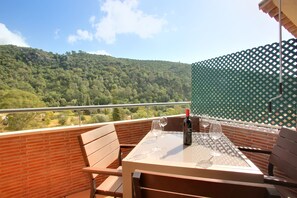 A balcony with a table, chairs, and a bottle of wine.