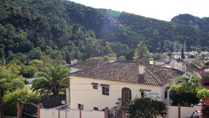 A traditional building with a tiled roof, surrounded by lush greenery and hills.