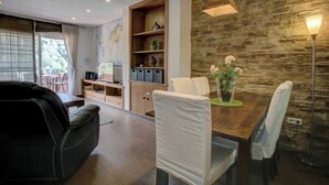 A modern living room with a sofa, dining table, chairs, a wooden cabinet, and a stone wall.