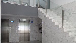 Ein modernes Interieur mit Marmorwänden, einer Treppe und zwei Aufzügen.