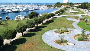 Un porto turistico con barche, un percorso curvo e aree verdi con alberi e arbusti.