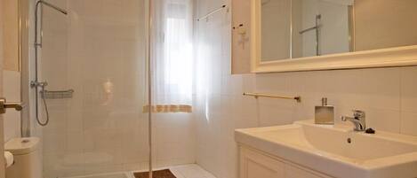 A modern bathroom with a shower, toilet, and sink.
