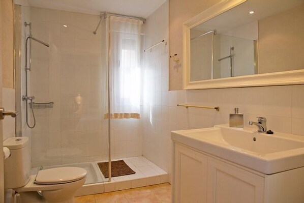 A modern bathroom with a shower, toilet, and sink.
