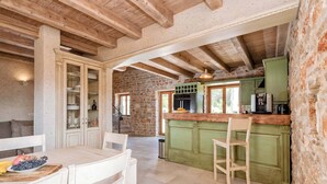 Una cocina rústica con vigas a la vista, una pared de piedra y una isla de encimera verde.