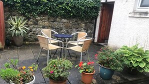 Un pati amb una taula i cadires, envoltat de plantes en testos.
