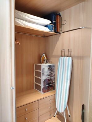 Efficient storage solutions are available in this well-organized closet with a shelf, drawers, and hanging space.