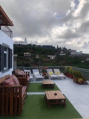 A rooftop terrace with lounge chairs, a wooden table, and potted plants. - BARROS APARTMENT: Offers views of the ocean and mountains—visit Madeira’s many attractions. (Estreito De Câmara)