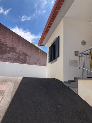 Ein Gebäude mit einer Betonwand, einer Treppe, die zu einer Tür führt, und blauem Himmel.