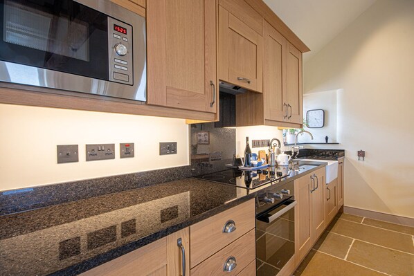 A modern kitchen with granite countertops, stainless steel appliances, wooden cabinets, and a built-in oven.