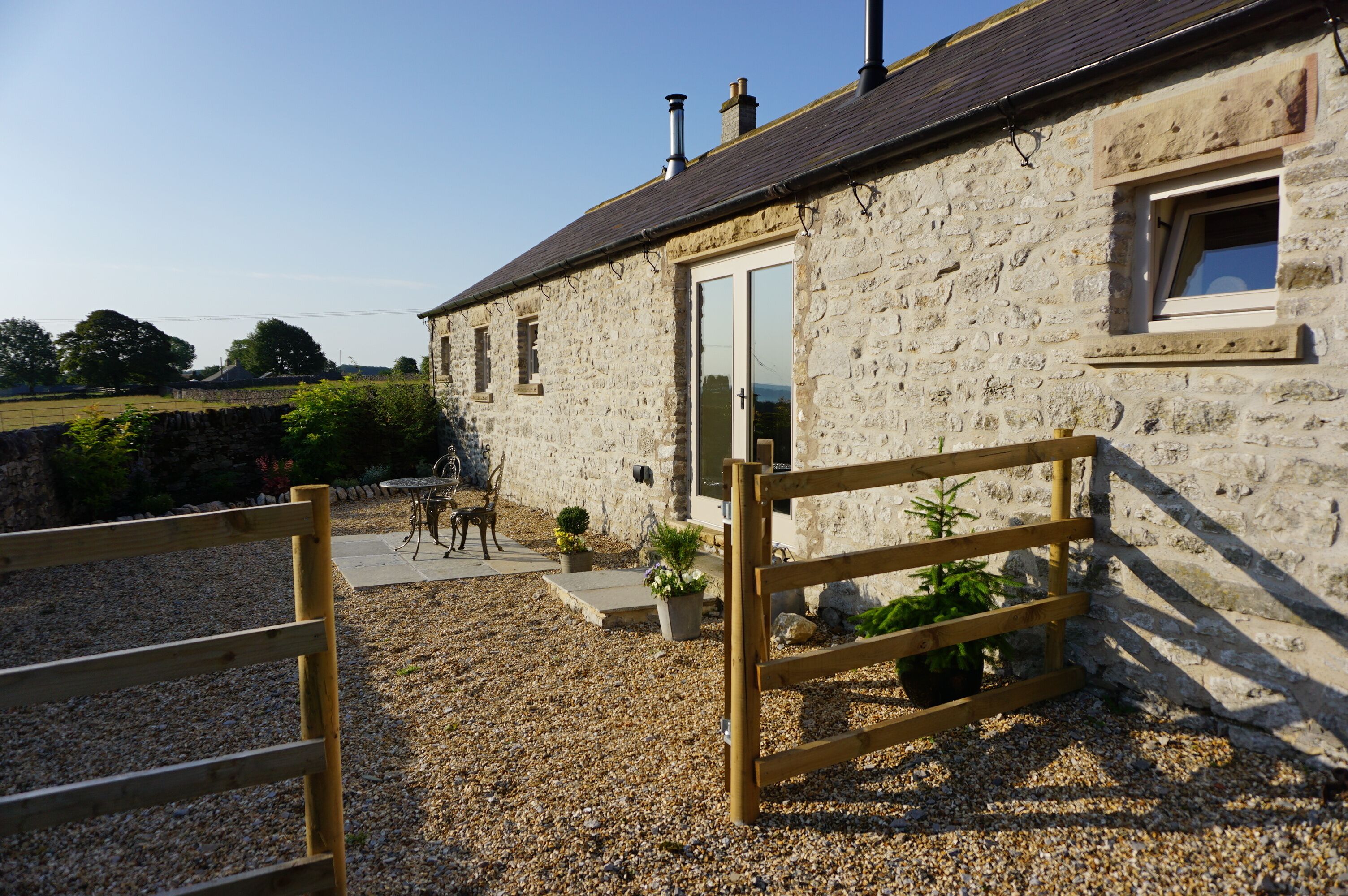 Un bâtiment en pierre avec une clôture en bois, une porte et une fenêtre.