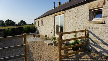 Un bâtiment en pierre avec une clôture en bois, une porte et une fenêtre.