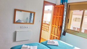 Um quarto com uma cama, um espelho, uma janela e uma porta.