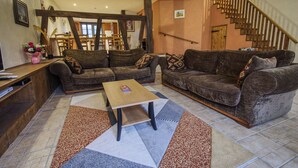 Un salon chaleureux avec un escalier en bois, un ensemble de canapés et une table basse.