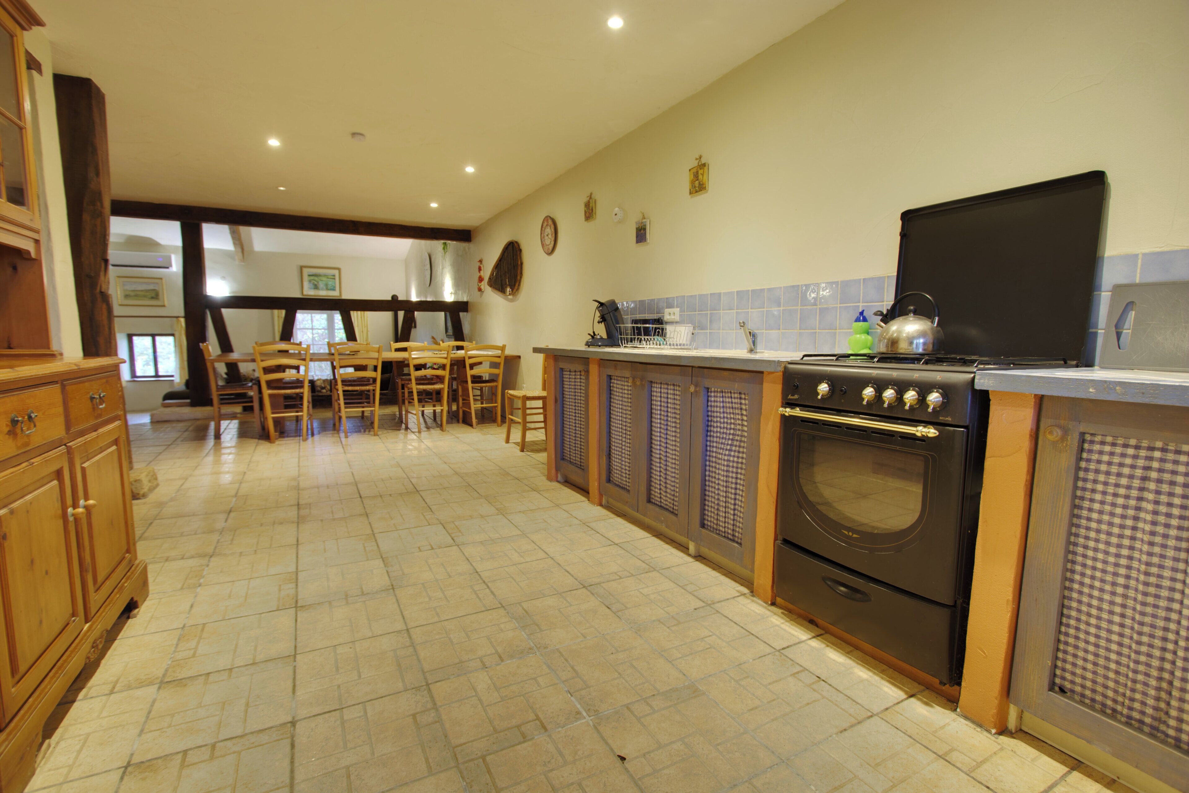 A spacious kitchen with a dining area, featuring a stove, oven, and wooden cabinets.