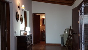 Un pasillo con techo de madera, un aparador con lámpara y una puerta que da a otra habitación.