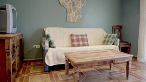 A living room with a sofa, a wooden coffee table, a stone wall decoration, and a television on a wooden stand.