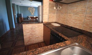 A kitchen with granite countertops, a stove, and a sink.
