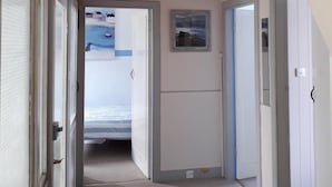 A hallway with a bed in the background, a ceiling light, and a door on the right. - Bute House - Great Sea Views! (Rothesay)