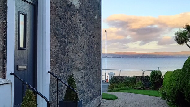 A stone building with a white door and a small staircase leading to the entrance. - Bute House - Great Sea Views! (Rothesay)