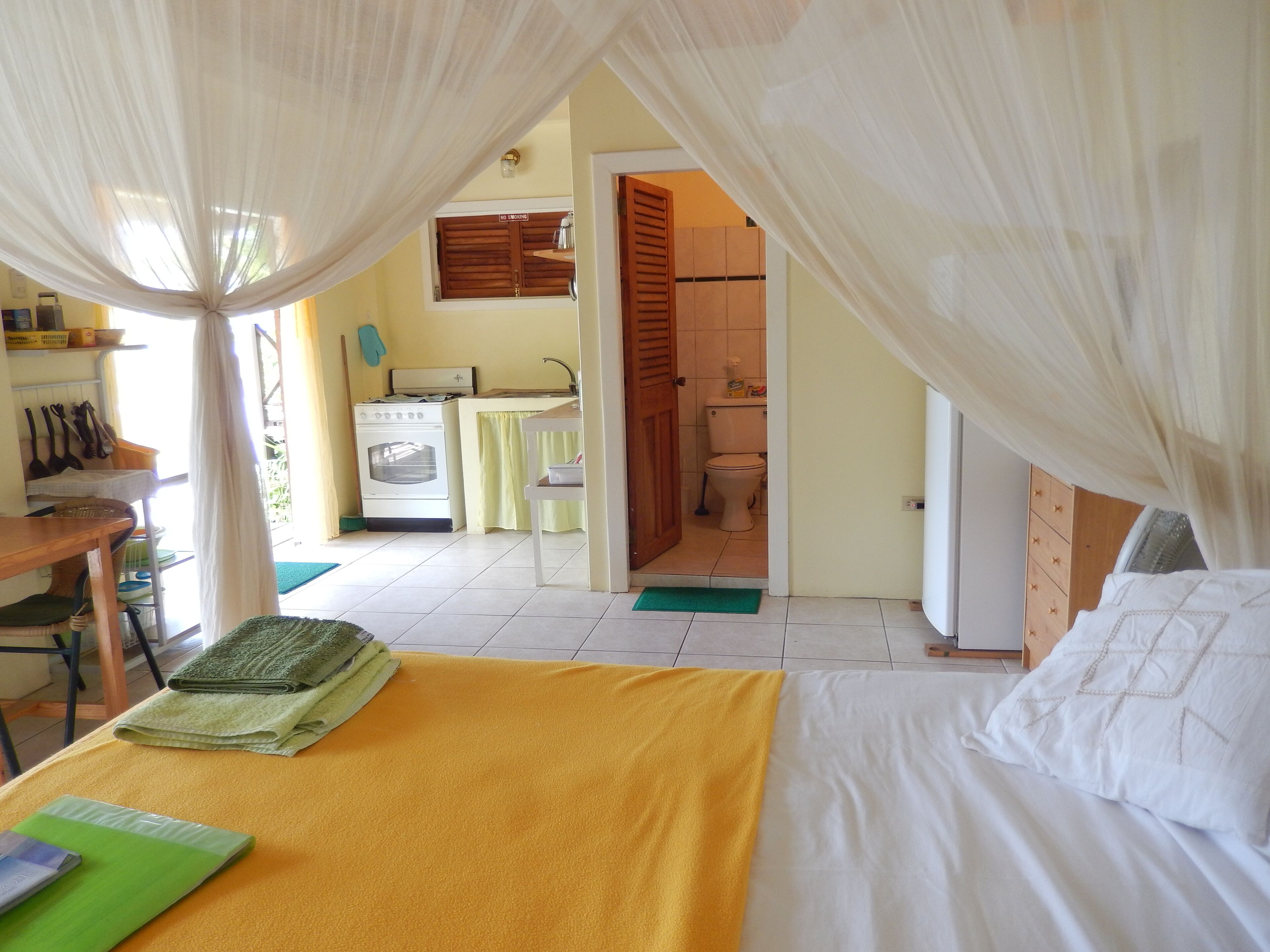 Une chambre à coucher avec un lit, un bureau et un coin cuisine à l’arrière-plan.