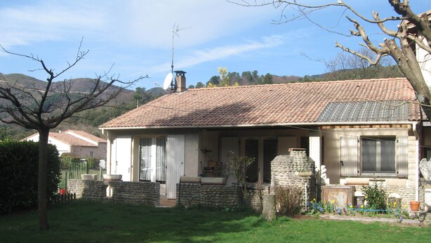 Ein Haus mit Ziegeldach, Steinmauern und einem kleinen Garten mit Topfpflanzen.