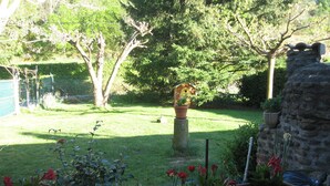 Ein Garten mit Steinmauer, Vogelhaus und verschiedenen Blumentöpfen.